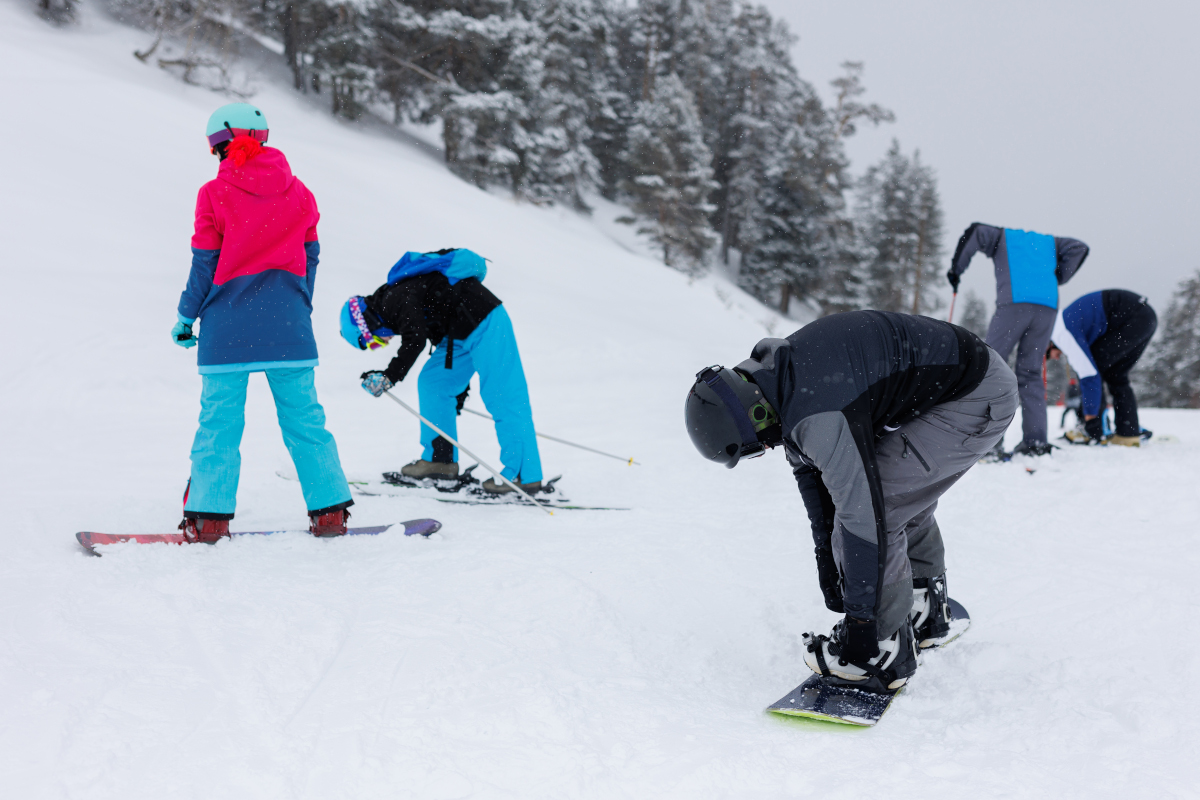 Group of tourists skiers and snowboarders stands at ski resort. Winter sports concept.